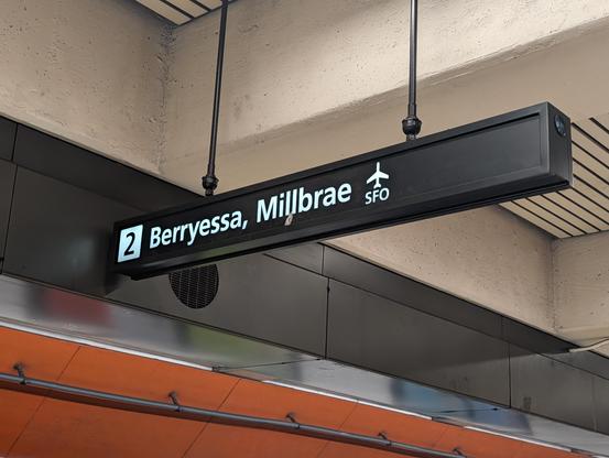 Bart platform sign that says berressa, Millbrae and a tiny SFO on top of the airplane.